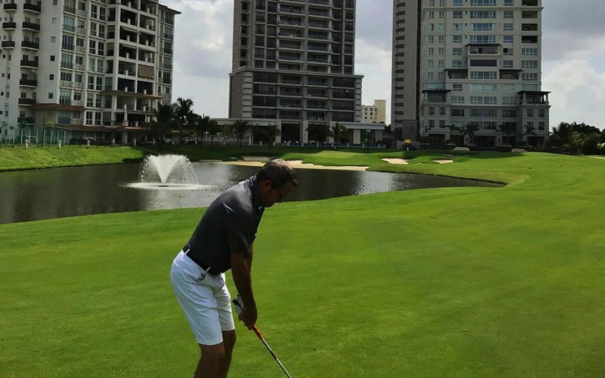 Chipping toward a green by the fountain lake, residences towering behind