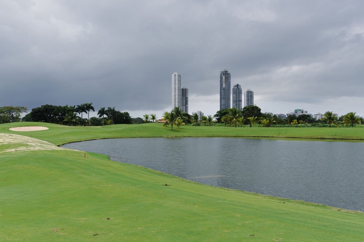 A fairway running toward a lake at Santa Maria, with Panama City towers on the horizon