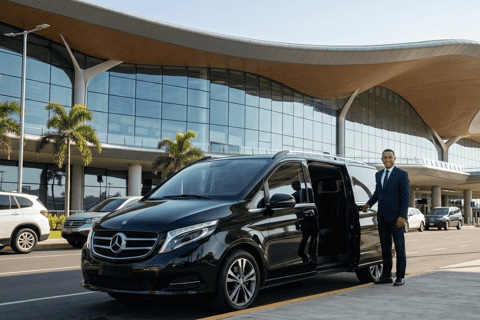 A driver in a suit holding the door of a black Mercedes van outside the terminal at Tocumen airport